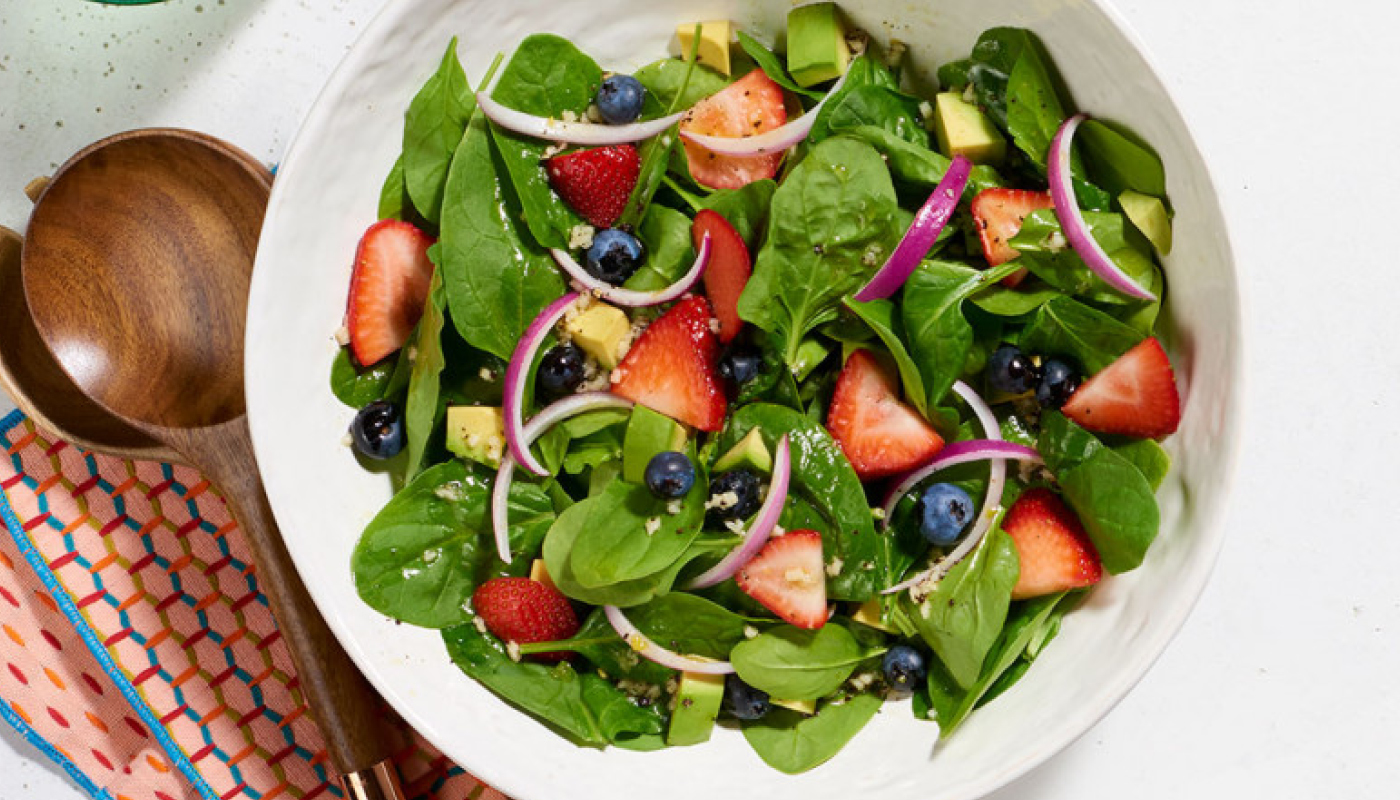 white salad bowl with spinach strawberry blueberries red onions