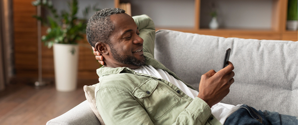 African American man on couch looking at breaking diabetes news on his smartphone
