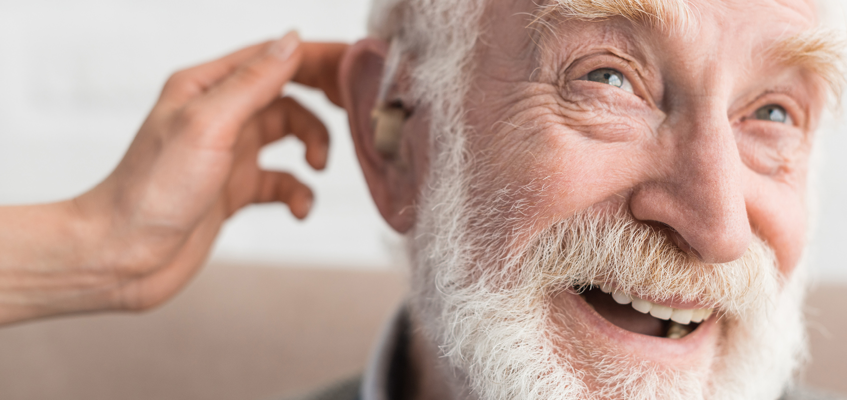 Woman's hand playfully touching a smiling senior man's ear