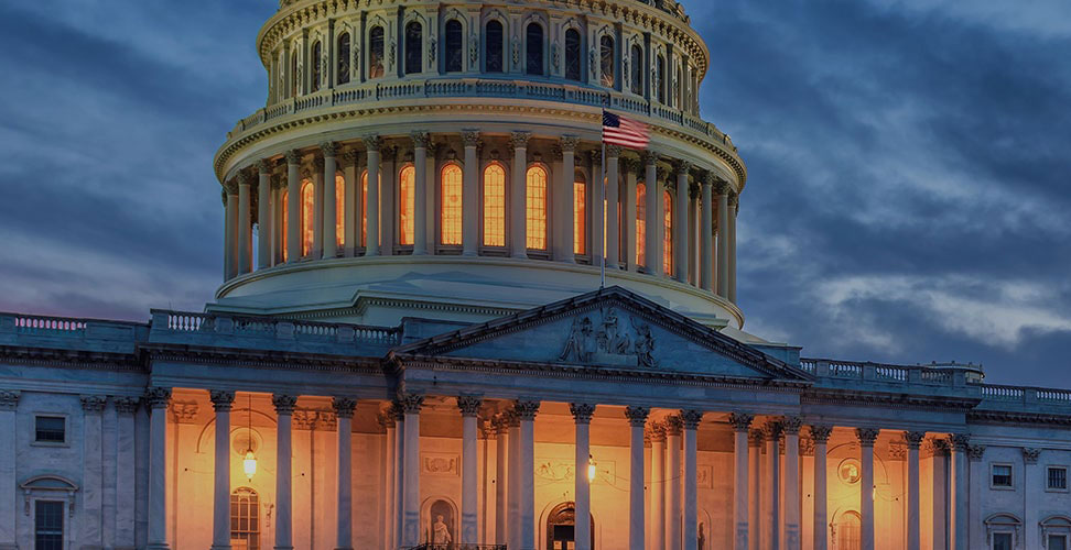 Close-up of U.S. capitol at dusk with rotunda and front porch lights on.