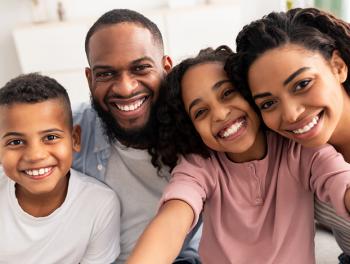 Happy African American family of son, father, daughter, and mother smiling.
