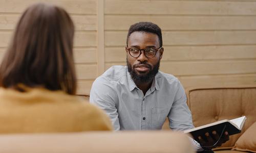 African American man with glasses talking to colleague