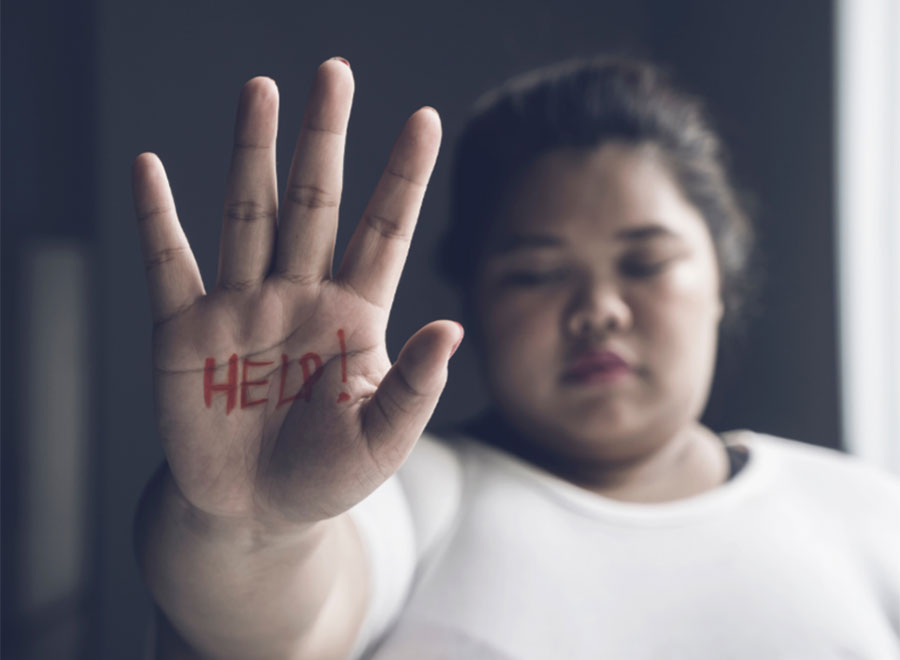 Young heavy girl holding open hand up with HELP written on her hand