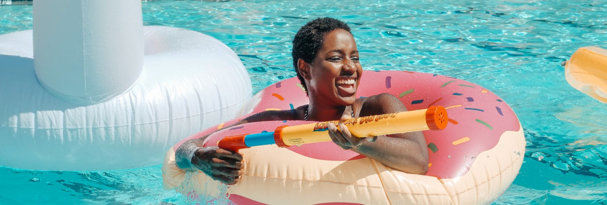 Smiling woman in pool with super soaker water toy