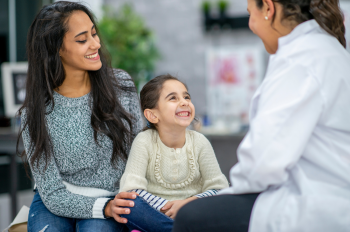 Smiling mother and daughter talking to doctor